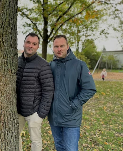 Sebastian und Lucas, die beiden Köpfe hinter Hüpfheini, vor einem Baum im Park.